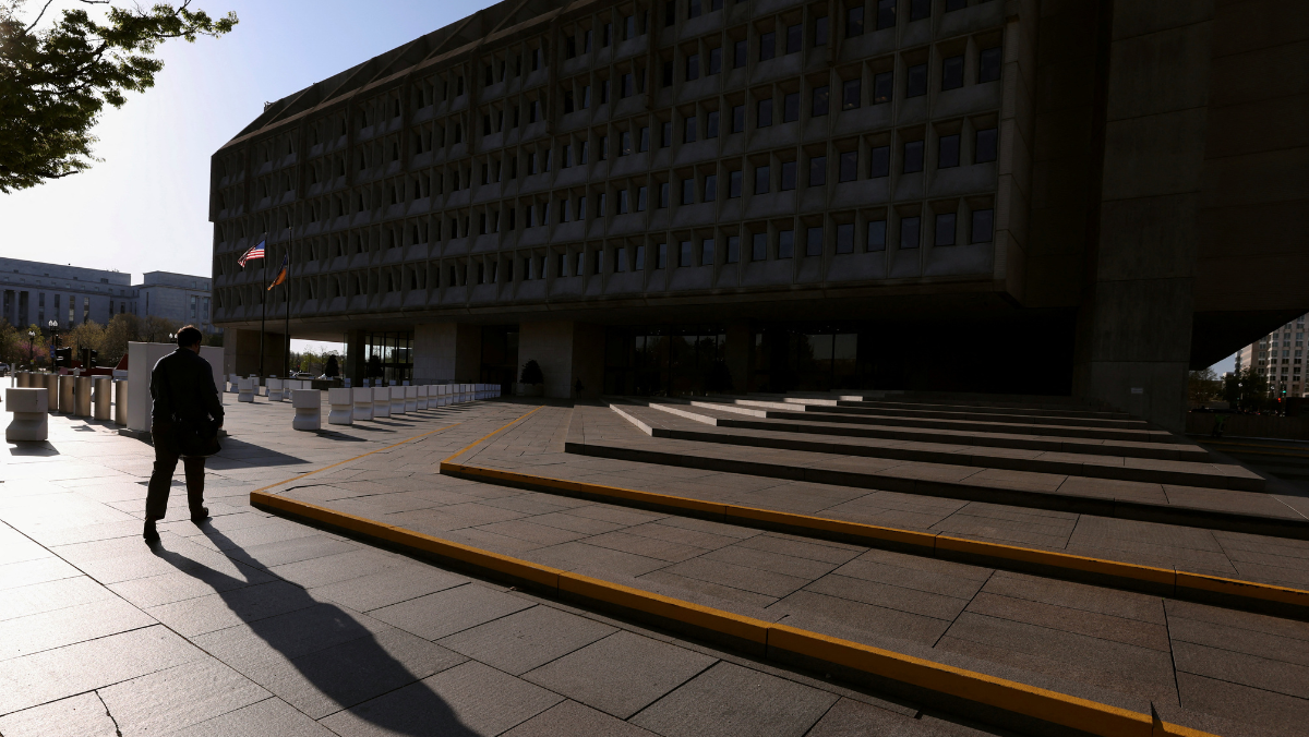 Person walking toward large federal building with strong morning shadows