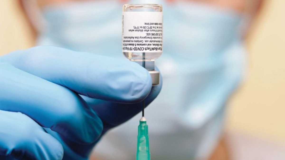 Gloved hand prepares syringe with mRNA vaccine vial.