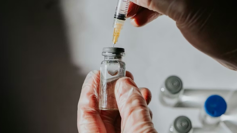 Gloved hand preparing vaccine dose from vial