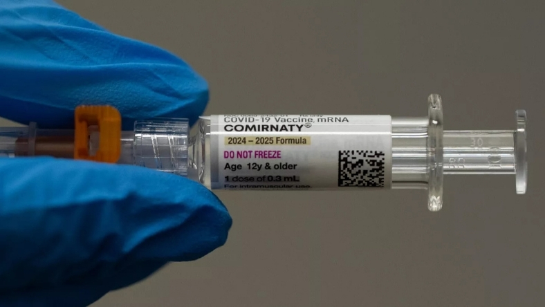Medical syringe containing mRNA vaccine held by healthcare worker in gloves