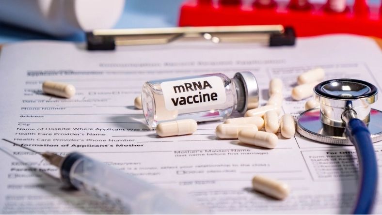 Labelled mRNA vaccine vial with syringe, capsules and stethoscope on medical form