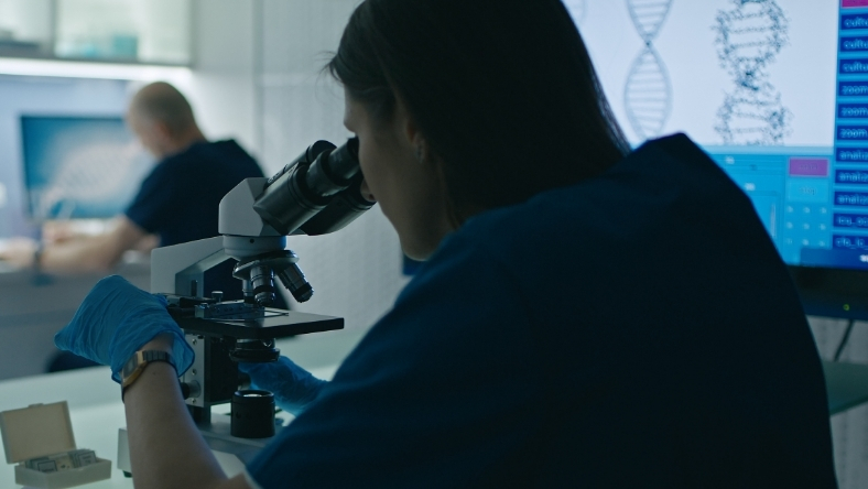 Researcher using microscope to analyze samples in laboratory