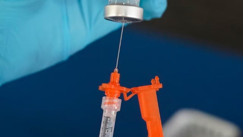 Syringe being filled with vaccine dose in laboratory setting